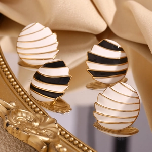 Detailed macro view of enamel sail-shaped earrings with gold plating on silk background