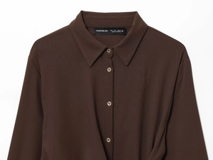 Détail d'une chemise marron foncé à manches longues avec boutons ambrés et col classique