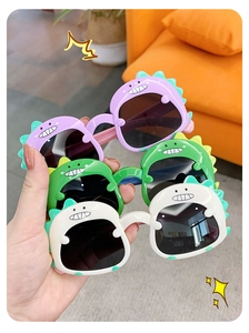 Close-up of cute dinosaur shaped kids sunglasses in purple green and white colors