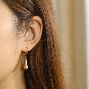 Macro detail of rose gold teardrop earring on model with elegant polished finish