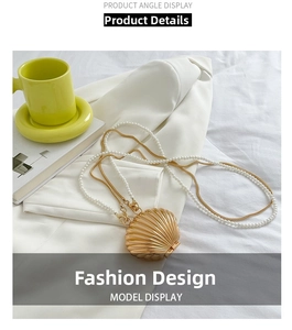 Detailed shot of golden shell evening bag with pearl and gold chain strap on soft fabric