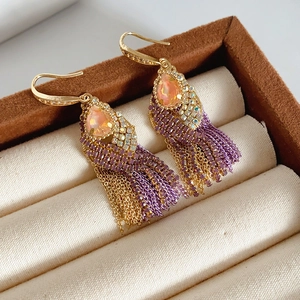 Macro detail of Bohemian gold earrings with purple tassels and pink zircon stones