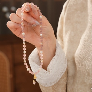 Detail of pink strawberry crystal and freshwater pearl bracelet with golden charm