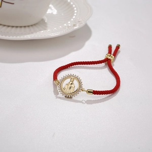 Detail of red cord bracelet with gold Virgin Mary pendant and inlaid zircon crystals