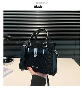 Close-up of black rhinestone handbag with silver padlock charm and adjustable strap