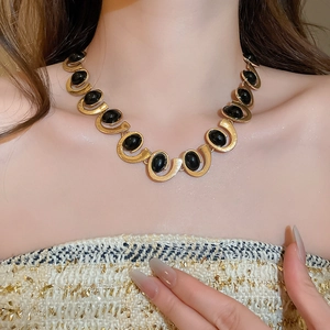 Detailed view of vintage gold necklace set with multiple black oval gemstones on model