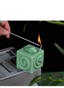 Detailopname van een brandende groene vierkante kaars met een slangreliëfpatroon