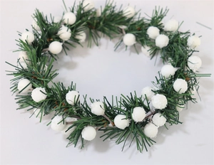 Close-up of PVC Christmas candle ring with green pine needles and white snowy berry clusters