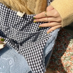 Detail of light blue plush tote bag with white embroidery and gingham fabric lining