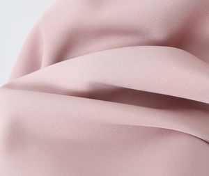 Close-up of pink textile fabric with soft matte texture and delicate plain weave structure