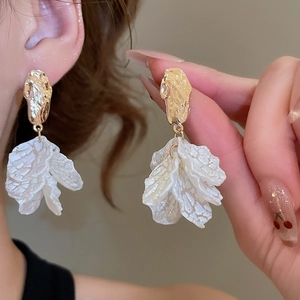 Detailed view of layered white petal tassels and gold textured metal dangle earrings