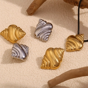 Close-up of golden and silver seashell earrings and necklace on a textured surface
