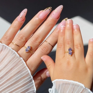 Close-up of mother and child wearing matching gold rings with purple marquise stones