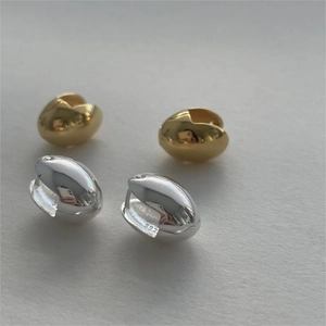 Detailed macro view of S925 sterling silver stamp on minimalist gold and silver hoop earrings