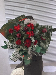 Close-up of red rose Christmas bouquet wrapped in festive green Christmas Day paper