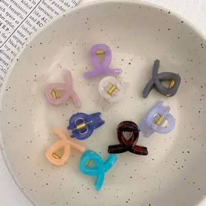 Set of 8 colorful mini knot hair claws in a ceramic bowl with a vintage newspaper