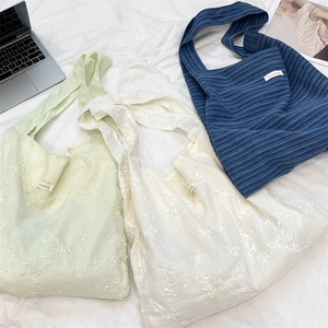 Detailed flat lay of three fabric tote bags with floral embroidery and ribbed texture