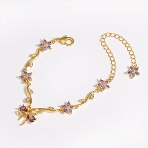 Close-up of golden bracelet featuring purple flowers and white leaf-shaped zirconias