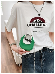 Detailed view of mini green chain bag with silver handle worn by a model