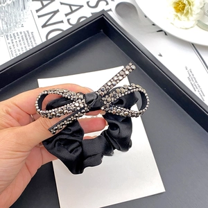 Detail of black satin hair scrunchie featuring a luxurious crystal bow embellishment