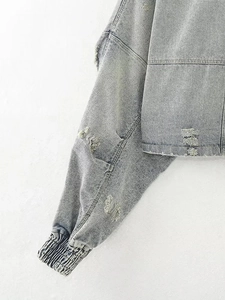 Detailed close-up of distressed denim jacket cuffs and frayed hems with street style texture