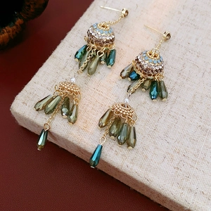 Detail of vintage gold tassel earrings with zircon flowers, pearls and green crystals