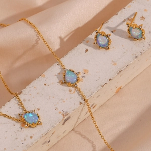 Detail view of pear-shaped blue opal necklace and earrings set on silk background