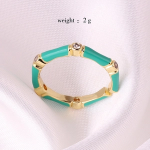 Bamboo style gold ring with green enamel and zircons on white satin background