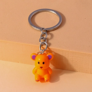Detail of cute orange resin bear keychain with purple ear accents and silver metal ring