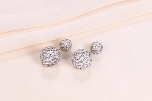 Macro shot of silver S925 shambhala crystal ball earrings on soft beige silk