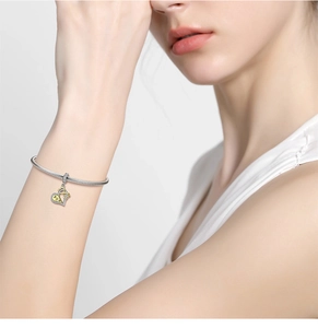 Close-up of silver snake chain bracelet with layered heart charm and zircon stones
