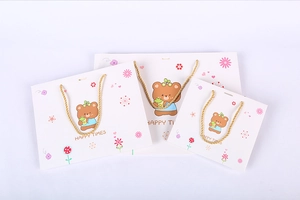 Three-piece stack of white gift bags with cute bears and golden rope handles