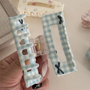 Detailed close-up of light blue checkered hair claw clip with black bow prints
