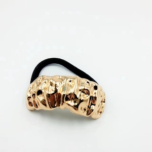 Detailed macro view of the irregular gold metal texture on a black elastic hair tie