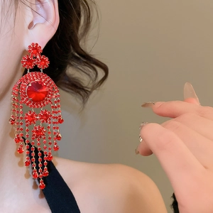 Close-up of elegant red tassel earrings with crystal rhinestones on a female model