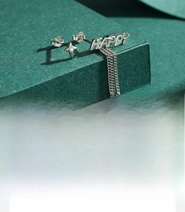 Detail of S925 sterling silver asymmetrical earrings with star and HAPPY tassel pendant