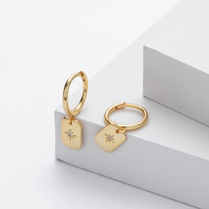 Detail of S925 silver gold-plated hoop earrings with engraved star and zircon charms