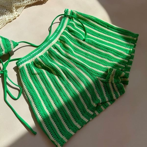 Detail of green and beige striped crochet beach shorts with drawstring waist for summer