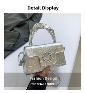 Détail du sac à main argenté effet crocodile avec boucle cristal et anse plissée