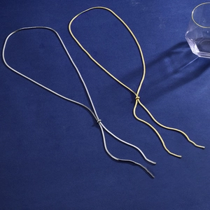 Elegant gold and silver flat snake chain necklaces on a textured deep blue background