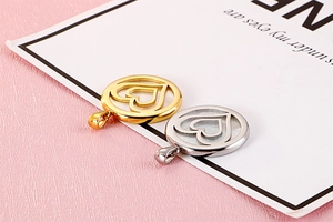 Detail of gold and silver stainless steel round hollow heart pendants on a card