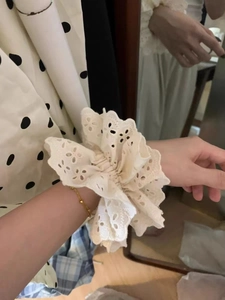 Detail of white lace embroidery scrunchie with scalloped edges worn on wrist