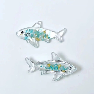 Detail of transparent shark resin pendants with blue stones and gold foil flakes inside
