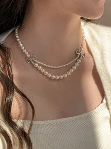Détail d'un collier de perles double épaisseur avec un nœud serti de diamants sur un mannequin
