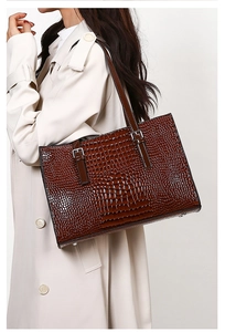 Detail of dark brown crocodile pattern texture on large tote bag with silver buckle