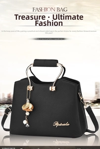 Detail of black textured handbag with golden circular handle and floral charm accessory