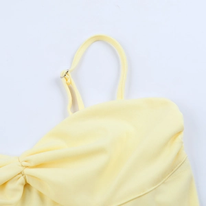 Close-up of adjustable straps and ruched detailing on a pale yellow mini dress
