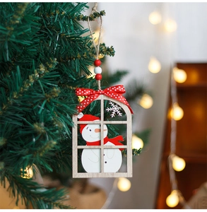 Detail of wooden snowman window ornament with red bow on a green Christmas tree