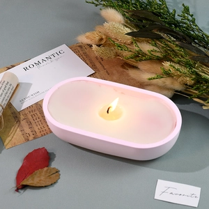 Close-up of a lit aromatherapy candle in a pink oval boat-shaped silicone mold