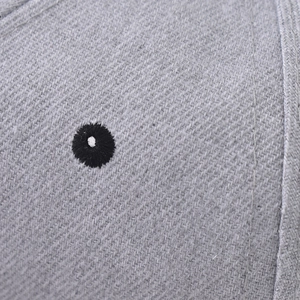 Detailed macro view of black embroidered eyelet on grey twill fabric for baseball caps